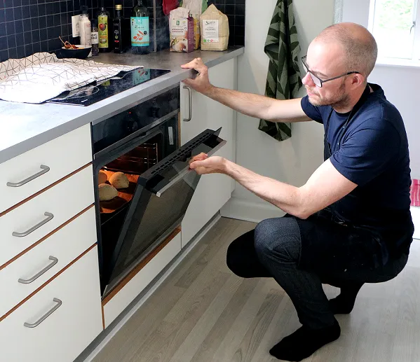 Jesper kigger ind i ovnen og ser hvordan bollerne klarer sig på bagestenen.